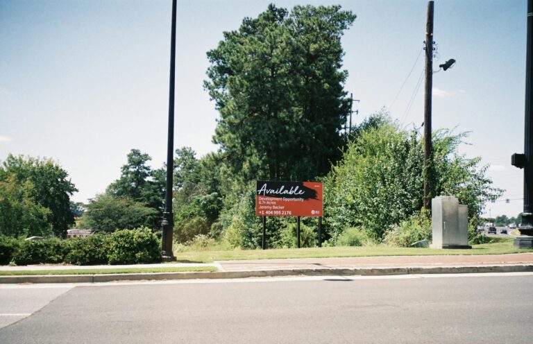 Vacant lot in Atlanta featuring a development opportunity sign amidst greenery.
